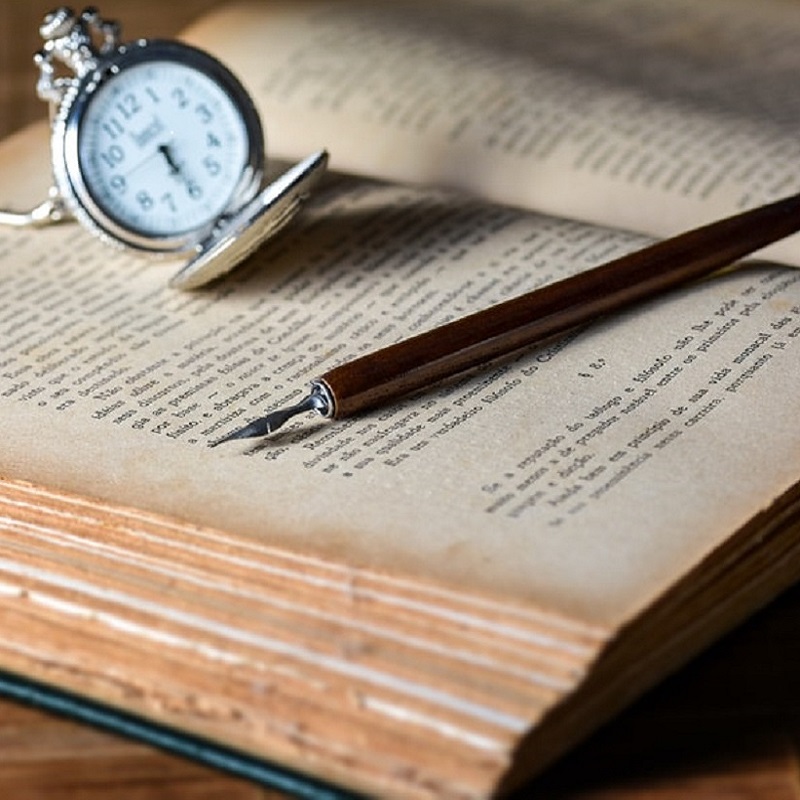 Five books about time that are worth your time. Open pocket watch and fountain pen set on top of an open book.