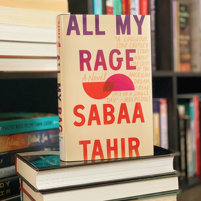 Hardcover edition of All My Rage placed upright on top of a stack of books.