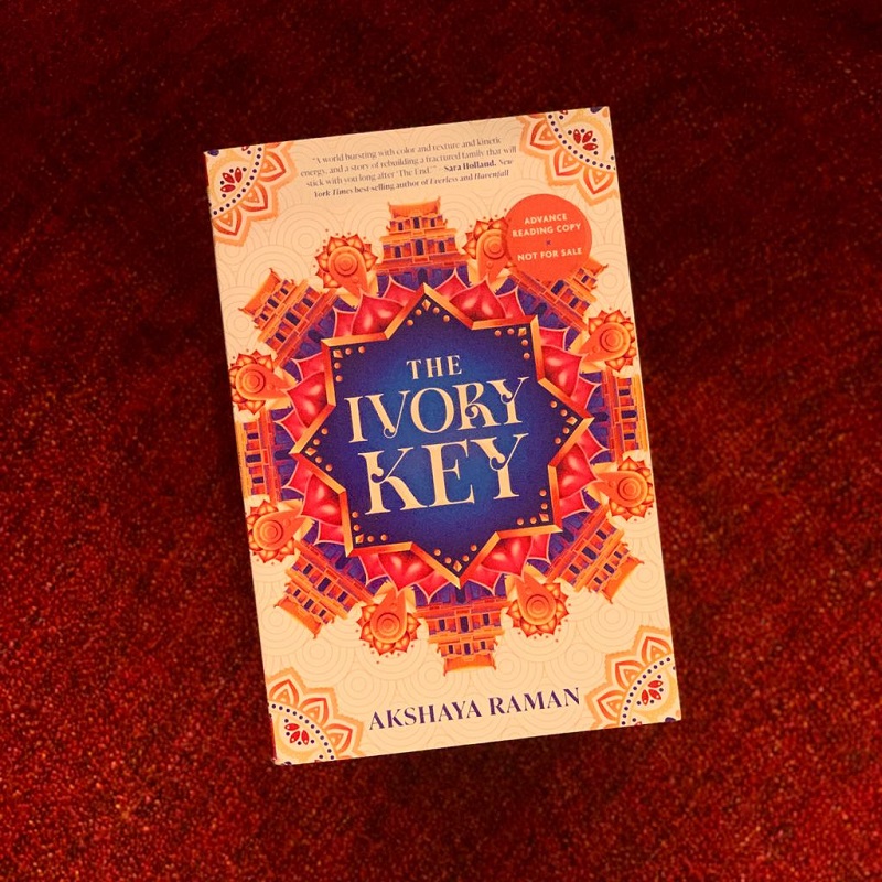 The Ivory Key in paperback above a red blanket.