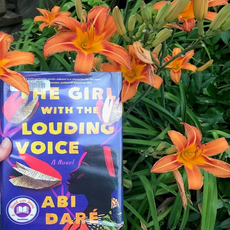 A picture of the The Girl with the Louding Voice book cover, lilies in background